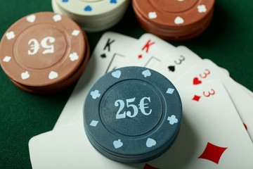 Chips with cards for poker game on green table in casino