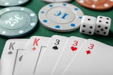 Chips with cards and dices for poker game on green table in casino