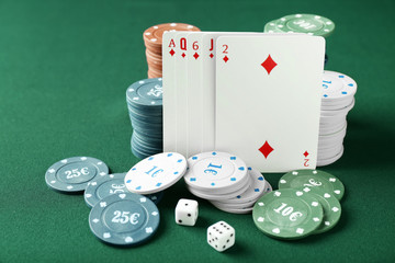 Chips with cards and dices for poker game on green table in casino