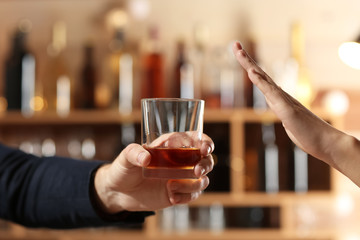 Man with glass of whiskey and woman refusing to drink in bar