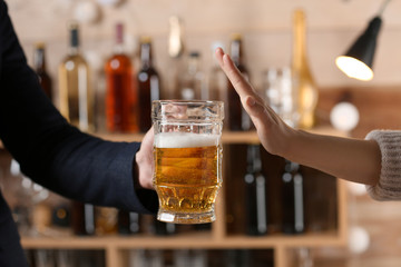 Man with mug of beer and woman refusing to drink in bar