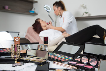 Decorative Cosmetics And Makeup Tools At Beauty Salon, Beautician And Customer In Blur Background