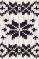 Knitted black and white Christmas ornament. Winter background. Handmade texture    