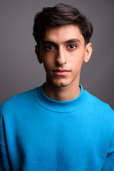 Fototapeta premium Young handsome Persian teenage boy against gray background