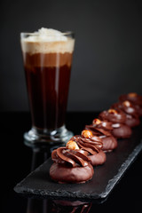  Chocolate dessert with hazelnut and coffee with cream on a black background.