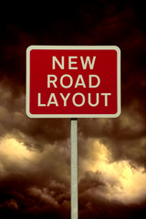 RED NEW ROAD LAYOUT WARNING SIGN WITH STORMY SKY AND CLOUDS IN BACKGROUND