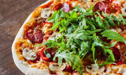 Pizza with Mozzarella cheese, mushrooms, pepperoni, tomato sauce, salami, pepper, Spices and Fresh arugula. Italian pizza on wooden table background