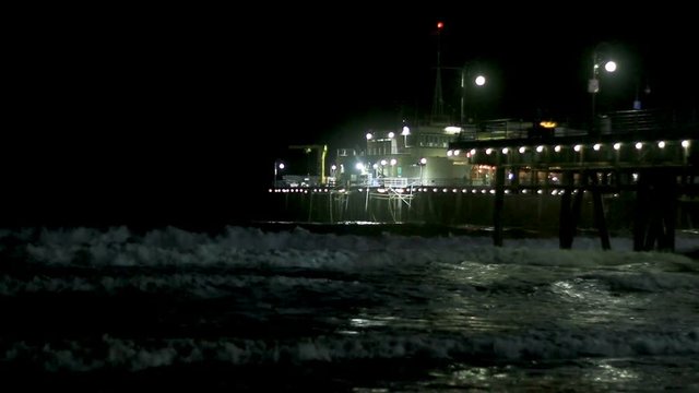 Blue lights on ocean waves next to pier