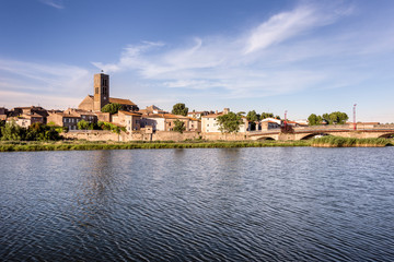 Fototapeta premium France, Trebes, near Carcassonne: Panorama skyline view of French small town with Aude river, Church Saint Etienne, cityscape, skyline bridge and blue sky in the background - concept travel history