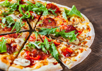 Pizza with Mozzarella cheese, mushrooms, pepperoni, tomato sauce, salami, pepper, Spices and Fresh arugula. Italian pizza on wooden table background