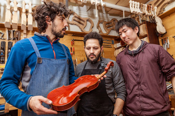 Fototapeta na wymiar group of craftsmen violinmakers testing a new violin
