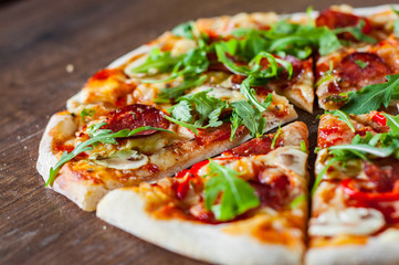 Pizza with Mozzarella cheese, mushrooms, pepperoni, tomato sauce, salami, pepper, Spices and Fresh arugula. Italian pizza on wooden table background