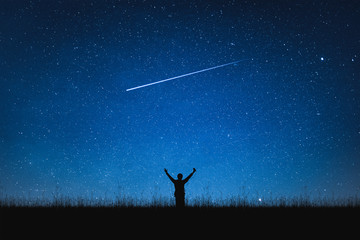 Silhouette of traveler standing on mountain and night sky with stars. Space background.