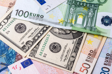 Euro banknotes and American Dollars bills of various denominations close-up.