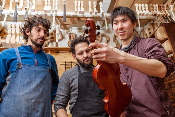 group of craftsmen violinmakers testing a new violin
