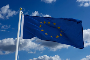 EUROPEAN UNION BLUE FLAG WITH GOLD STARS AND BLUE SKY WITH WHITE CLOUDS