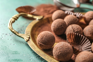 Metal tray with tasty chocolate truffles on color table