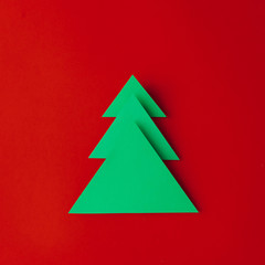 Minimal paper art Christmas tree on red background. Flat lay. New Year concept.