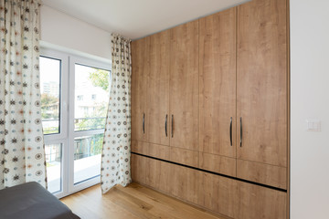 Guest room with wooden closet and balcony door in modern house