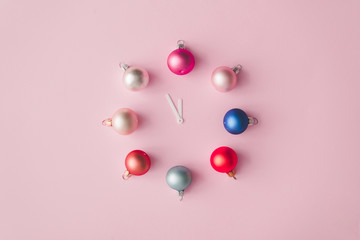 Clock hands with colorful pastel decoration balls on pink painted wall. Minimal time concept....