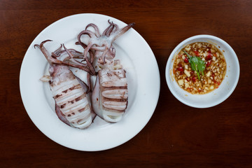 Grilled squid with dipping sauce on white plate
