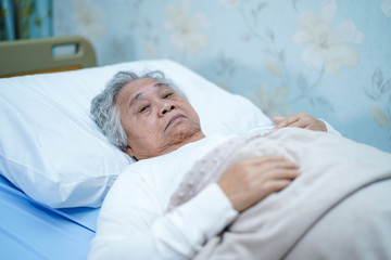 Asian senior or elderly old lady woman patient smile bright face with strong health while lying on bed in nursing hospital ward : healthy strong medical concept 