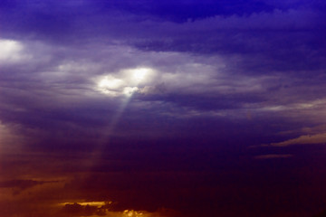 through the clouds over the sea a ray of sunshine makes its way