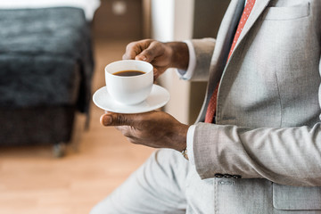 cropped view of elegant african american man holding cup of coffee