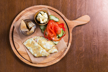Omelette with vegetables and bread on wooden table in the restaurant. Tasty food. Gourmet