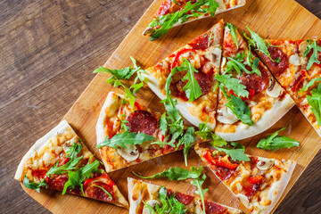 slices Pizza with Mozzarella cheese, mushrooms, pepperoni, tomato sauce, salami, pepper, Spices and Fresh arugula. Italian pizza on wooden table background