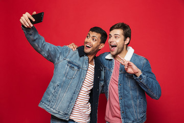 Two cheerful young men standing isolated over red