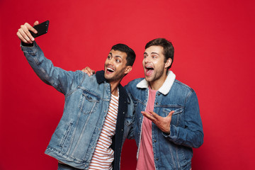 Two cheerful young men standing isolated over red