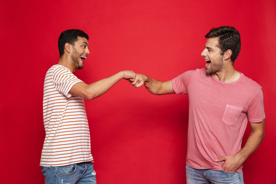 Two cheerful young men standing isolated over red