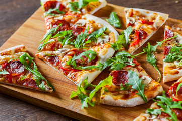 slices Pizza with Mozzarella cheese, mushrooms, pepperoni, tomato sauce, salami, pepper, Spices and Fresh arugula. Italian pizza on wooden table background