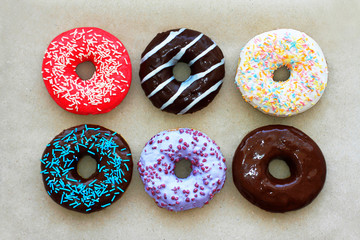 Donuts of different colors on cardboard, top view