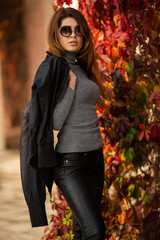 Photo of long-haired woman in sunglasses on background of autumn red ivy