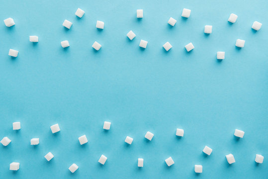 top view of white sugar cubes with copy space on blue background