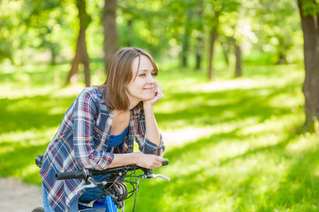 Fototapeta na wymiar Happy young beautiful woman with bicycle in a park. Empty space for text