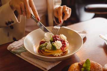 Girl has breakfast with fresh pancakes with cream