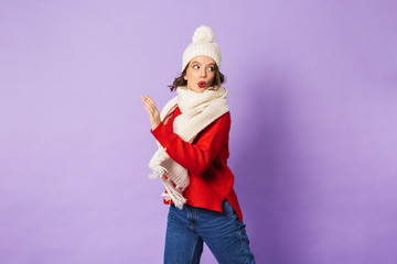 Fototapeta na wymiar Shocked young woman wearing winter hat isolated over purple background.