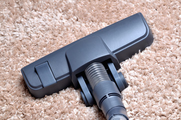 Head of vacuum cleaner on shaggy carpet - close-up of noozle
