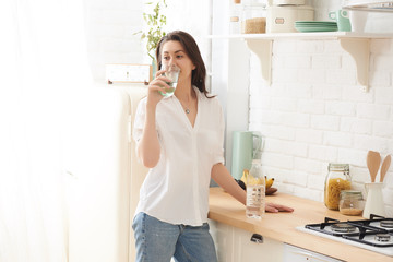 Young happy woman drinking coffee on the kitchen in the morning.