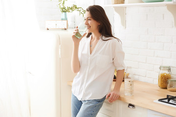 Fototapeta na wymiar Young happy woman drinking coffee on the kitchen in the morning.