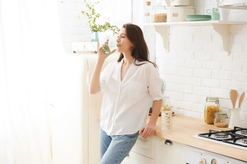 Young happy woman drinking coffee on the kitchen in the morning.