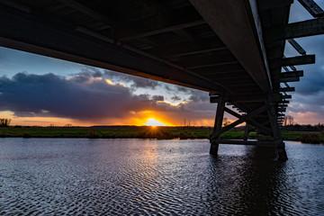 flusslandschaft, fluss, wiesen, holzbr&uuml;cke, sonnenunteergang, wolkenhimmel, wolken, wellen, reflektion, 