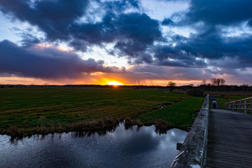 flusslandschaft, fluss, wiesen, holzbrücke, sonnenunteergang, wolkenhimmel, wolken, wellen, reflektion, 