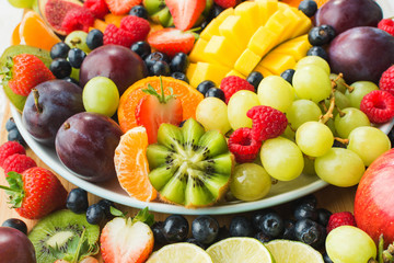 Naklejka na ściany i meble Assorted fruits and berries platter, strawberries blueberries, mango orange, apple, grapes, kiwis background, selective focus