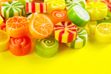 Multicolored caramel candies on a yellow background closeup