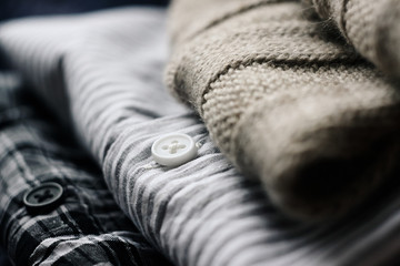 a stack of clothes prepared for the cold: it woolen sweater beige and two shirts with different patterns
