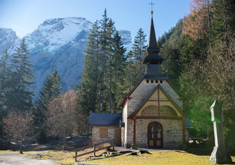 Fototapeta na wymiar Traveling. A church in the depths of a forest. Alpine mountains on the background